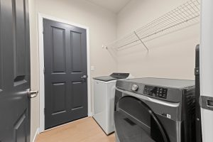 Laundry room of the updated Lacey home with washer, dryer and shelving.